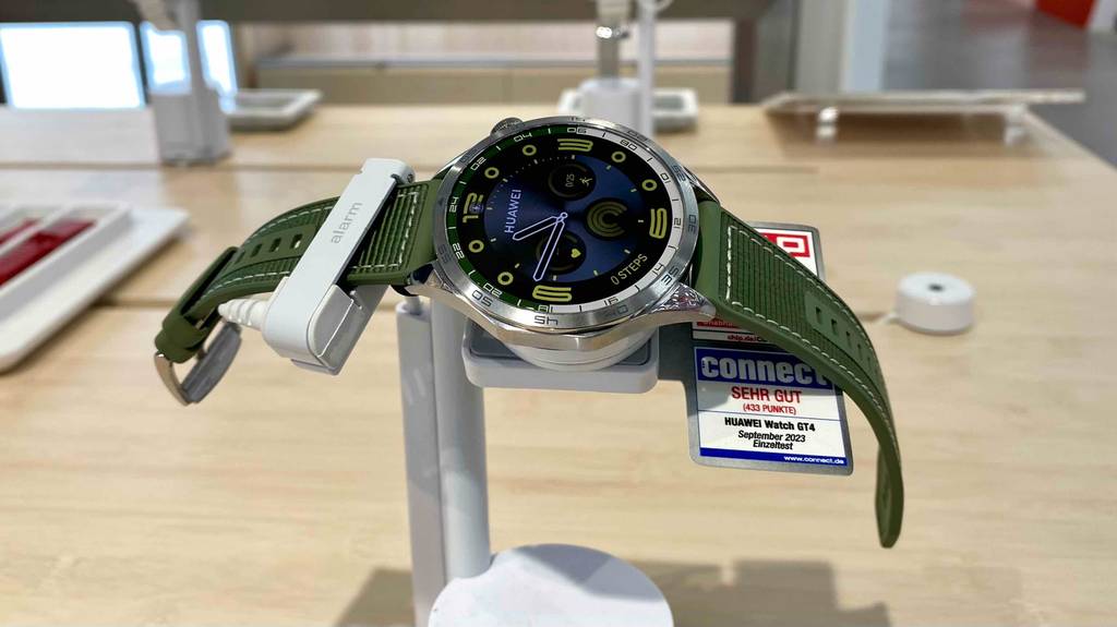 Gesamtansicht einer ausgestellten, eingeschalteten und getesteten Huawei-Smartwatch mit rundem Bildschirm sowie grünem Armband zum Verkauf ausgestellt.