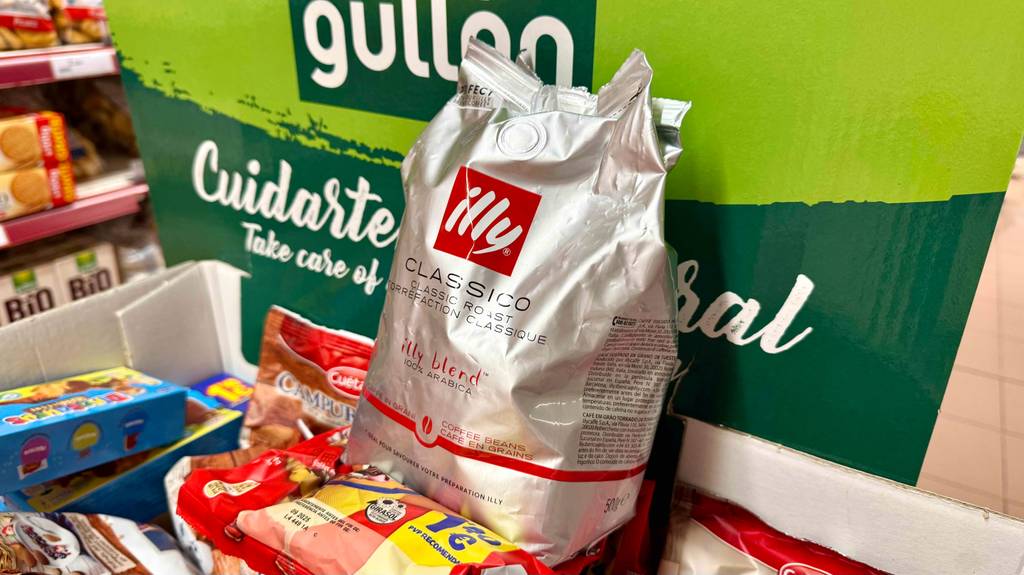 Eine silberfarbige Tüte mit getesteten illy-Kaffeebohnen steht auf anderen Lebensmitteln.