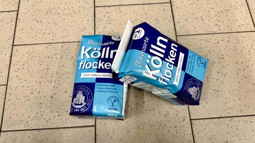 Zwei 500-g-Packungen mit Kölln-Haferflocken im Test befinden sich auf einem Fliesenboden.