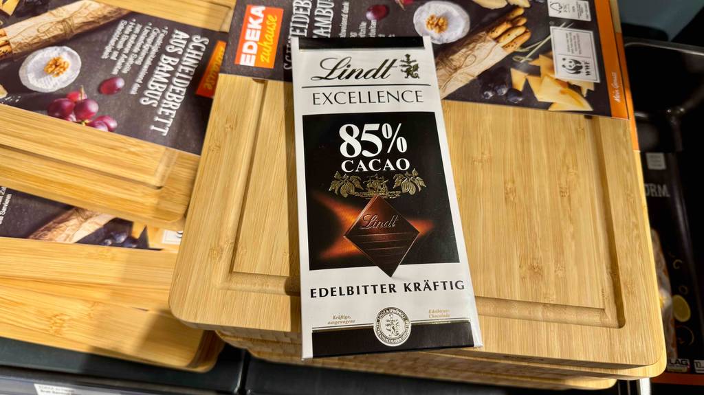 Eine Tafel getestete Lindt-Schokolade liegt auf einem Küchenbrett aus Holz im Verkaufsbereich.
