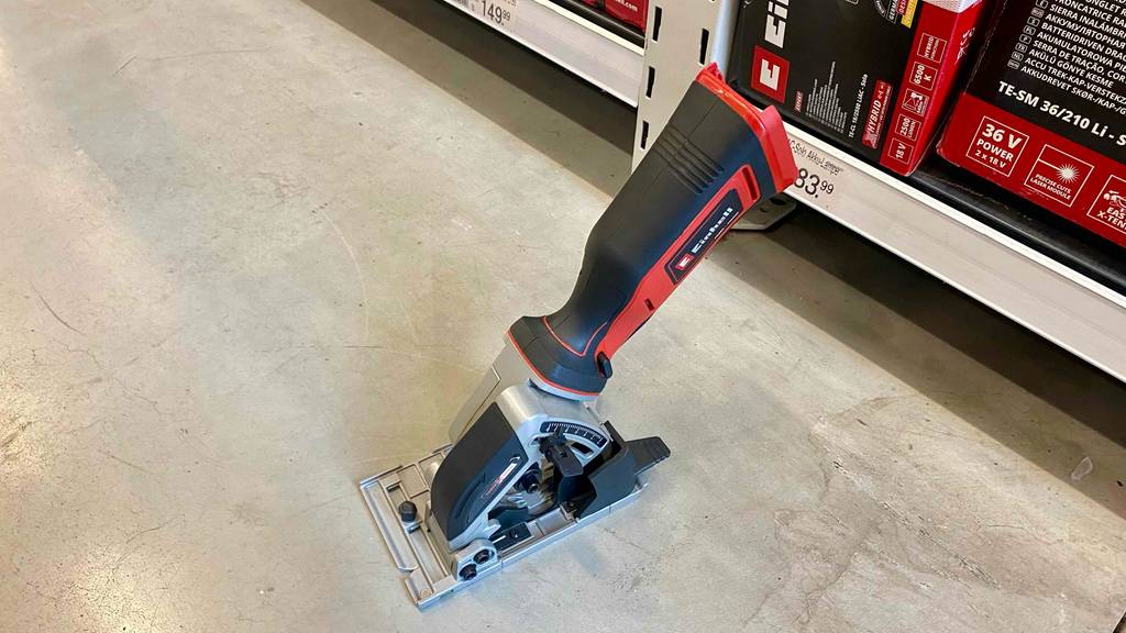 Ansicht von oben auf eine Einhell Mini-Handkreissäge im Test, mit Fokus auf den Handgriff, auf einem Zementboden in einem Verkaufsbereich.
