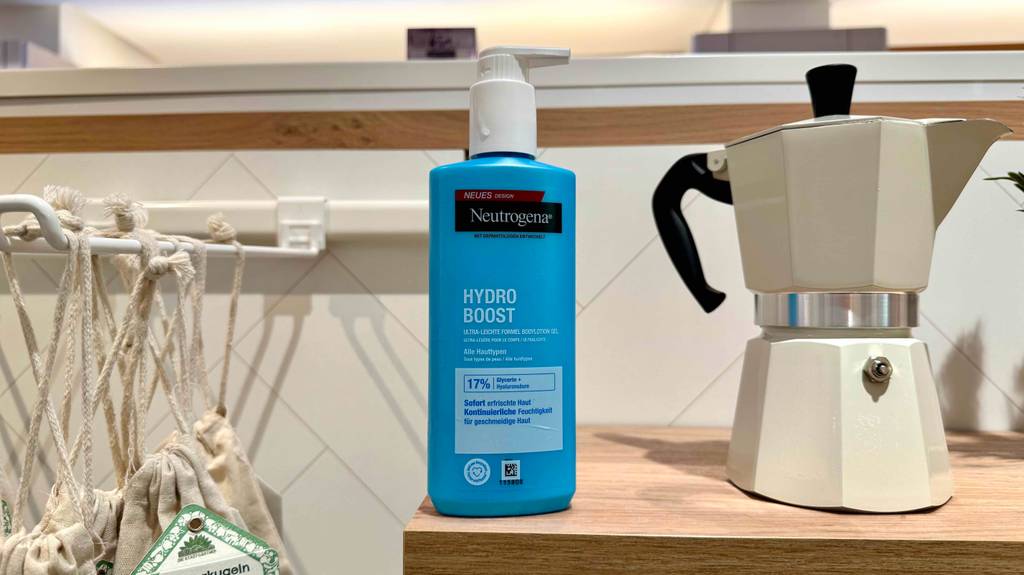 Getestete Neutrogena-Bodylotion im blauen Spender steht neben einer italienischen Kaffeekanne.