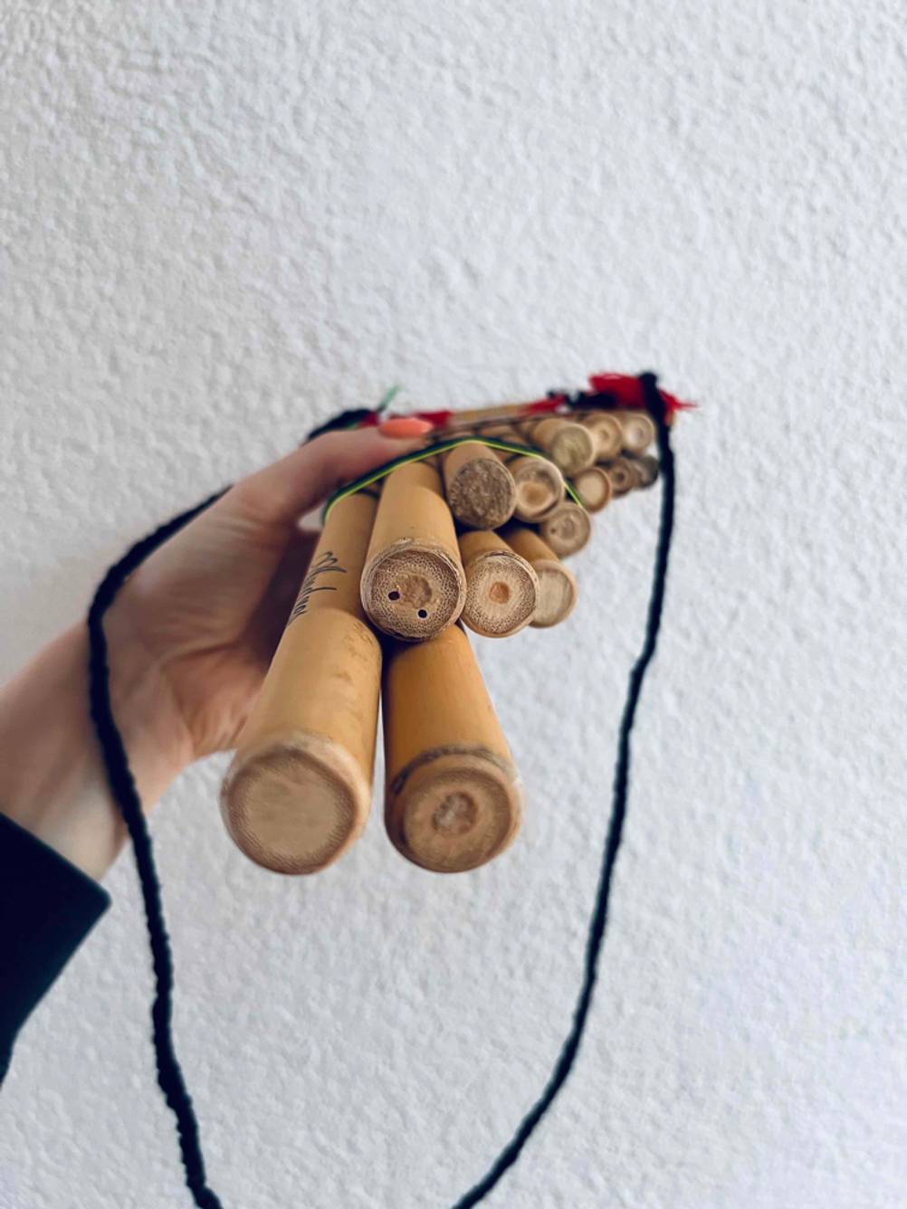 Hand hält getestete Panflöte von unten in die Kamera.