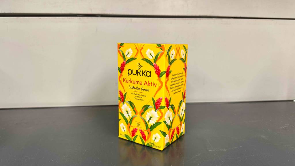 Bio-Pukka-Tee im Test: eine gelbe 36-g-Packung mit Kurkuma steht vor einer weißen Wand.