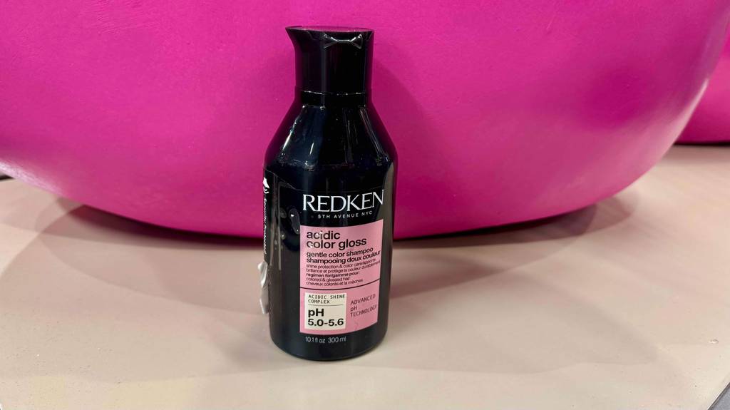 Redken-Shampoo im Test: Eine schwarze 300-ml-Kunststoffflasche steht vor einem pinkfarbenen Hintergrund.