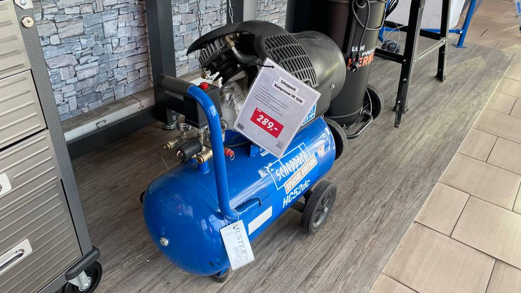 Scheppach-Kompressor mit 50 Liter Volumen im Test: Gesamtansicht des blauen Modells inklusive Preisschild, das in einem Verkaufsbereich steht.