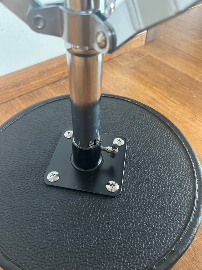 Getestet: Ein Schlagzeug-Hocker liegt auf seiner Sitzfläche mit schwarzem Lederbezug auf einem Holzboden.