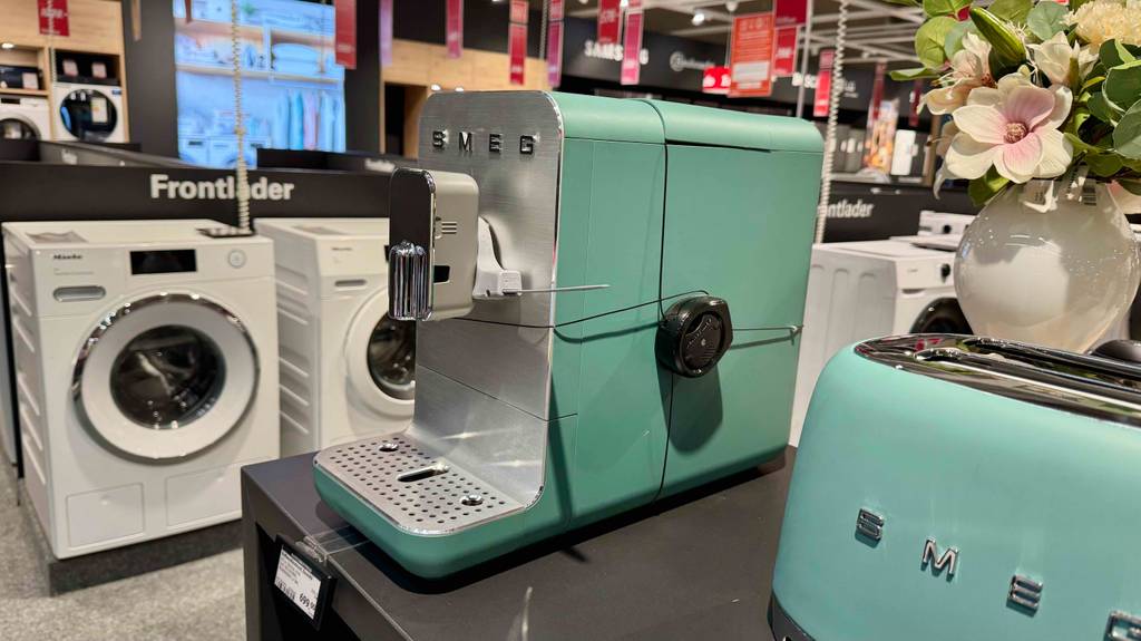 Seitenansicht des schmalen Kaffeevollautomaten im mintgrünen Design, wie er auf einer Ausstellungsfläche steht.