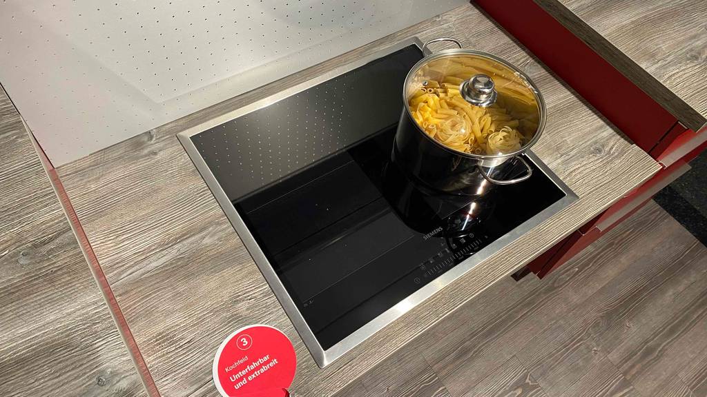 Ansicht auf ein getestetes Siemens-Induktionskochfeld in 60 cm Größe, auf dem sich ein Edelstahl-Topf mit Glasdeckel inklusive Nudeln befindet.