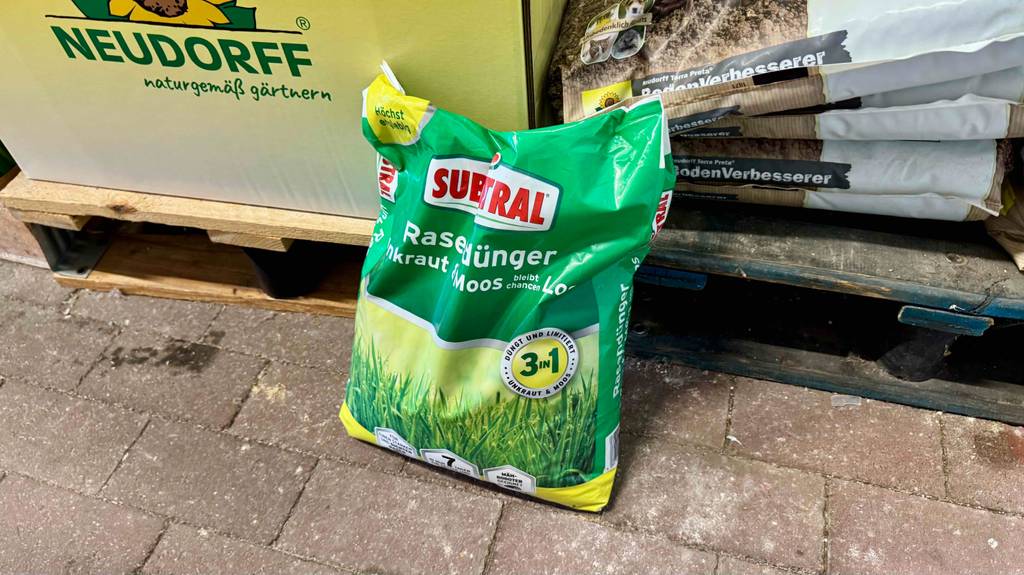 Getestet: Der Substral-Rasendünger in der 7,2-kg-Kunststofftüte lehnt an einer Palette mit Boden-Verbesserer.