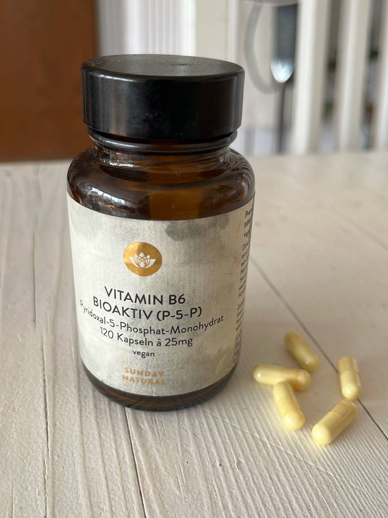 Neben einer blickdichten Braunglasflasche liegen mehrere Kapseln mit Vitamin B6 im Test.