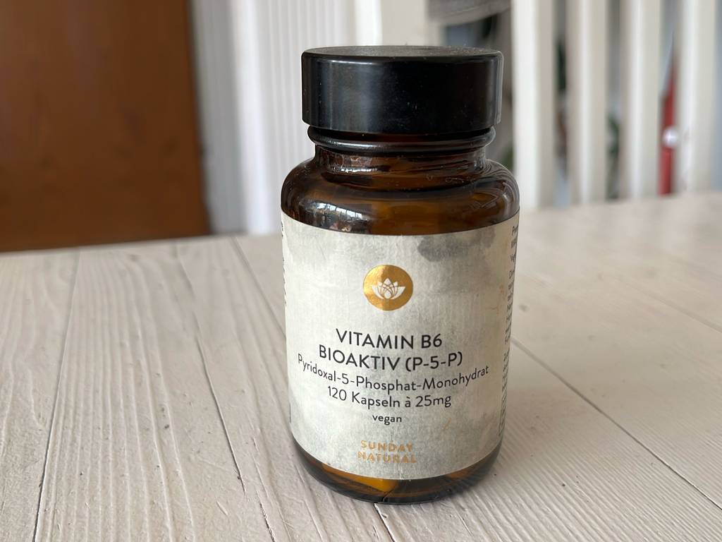 Vitamin-B6-Test: eine blickdichte Glasdose mit Drehverschluss steht auf einer weißen Holzfläche.