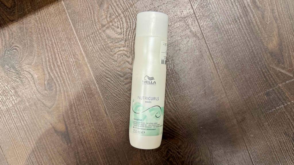 Im Test: Wella-Shampoo in einer weißen Kunststoffflasche liegt auf einem braunen Untergrund.