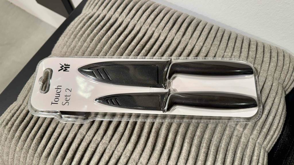 wmf messerset test: Ein WMF-Messerset mit zwei schwarzen Messern liegt auf einem hellgrauen Stoff.