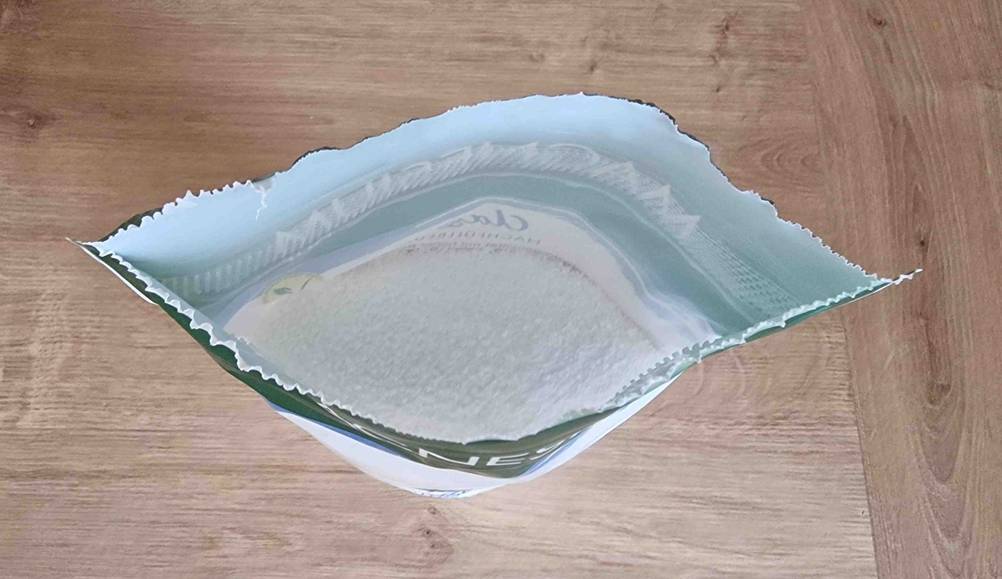 Magnesiumcitrat-Pulver-Test: Ansicht von oben auf einen geöffneten Kunststoff-Standbeutel mit Magnesium auf einer Holzfläche.