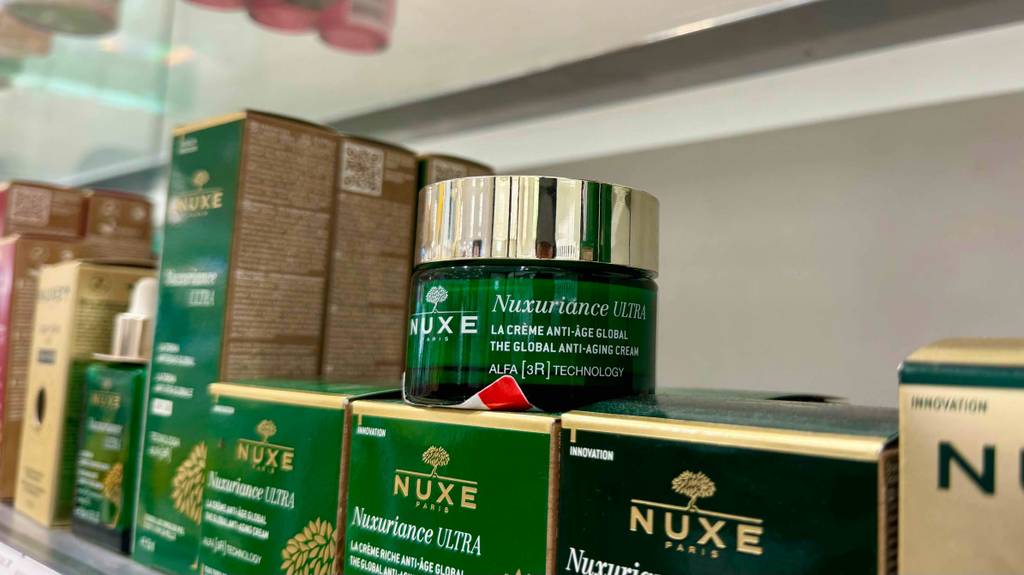 Auf einem Regal im Drogeriemarkt, auf dem sich mehrere Kosmetikartikel befinden, steht die getestete Gesichtscreme von Nuxe im 50-ml-Tiegel.