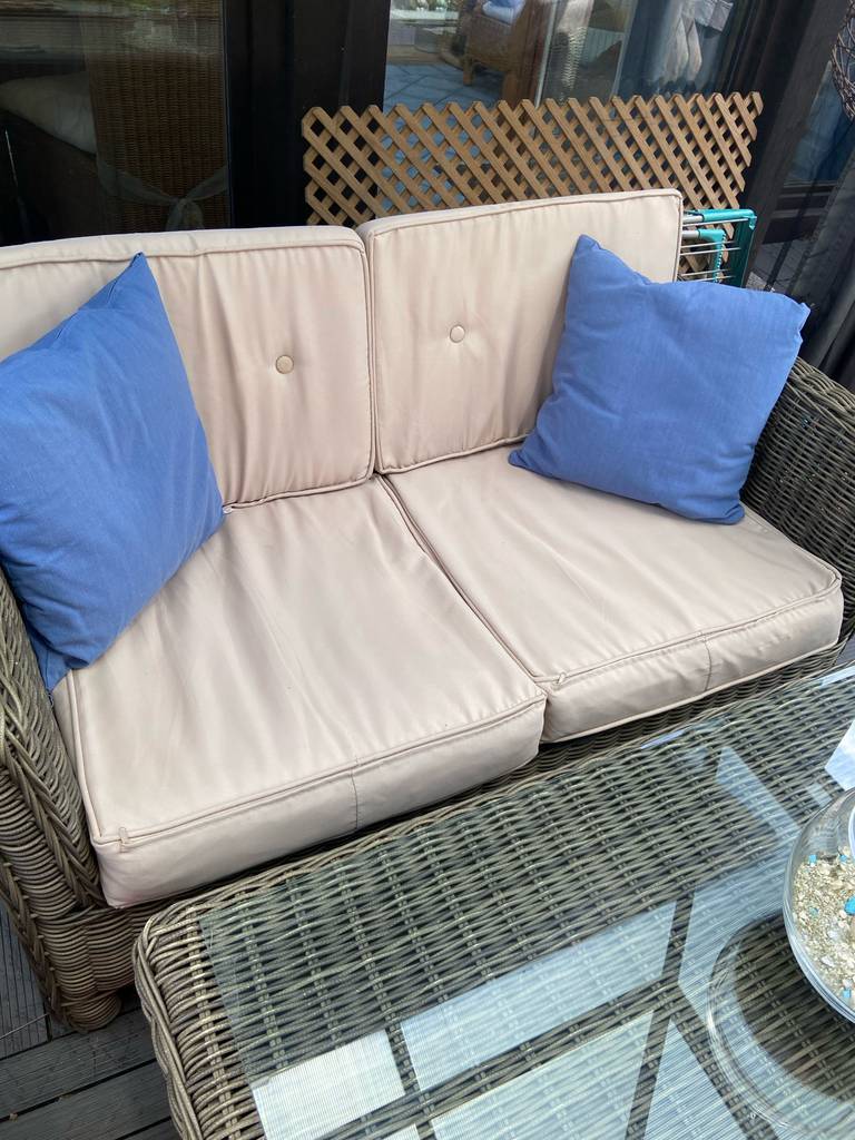 Rattan-Gartenmöbel im Test: Ansicht von vorn auf ein Rattan-Sofa inklusive zweier beigefarbener Sitzkissen.