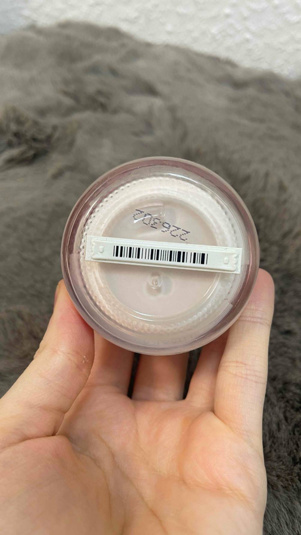 Rosencreme-Test: Ansicht des Tiegelbodens mit aufgeklebtem Barcode, der auf einer Handfläche liegt.