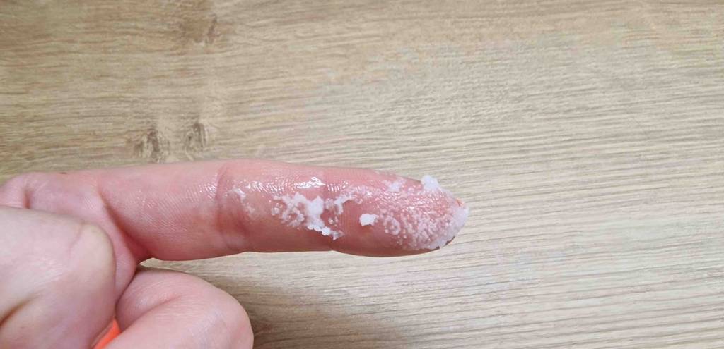 Sheabutter im Test: Sheabutter auf Zeigefinger vor Holzhintergrund.