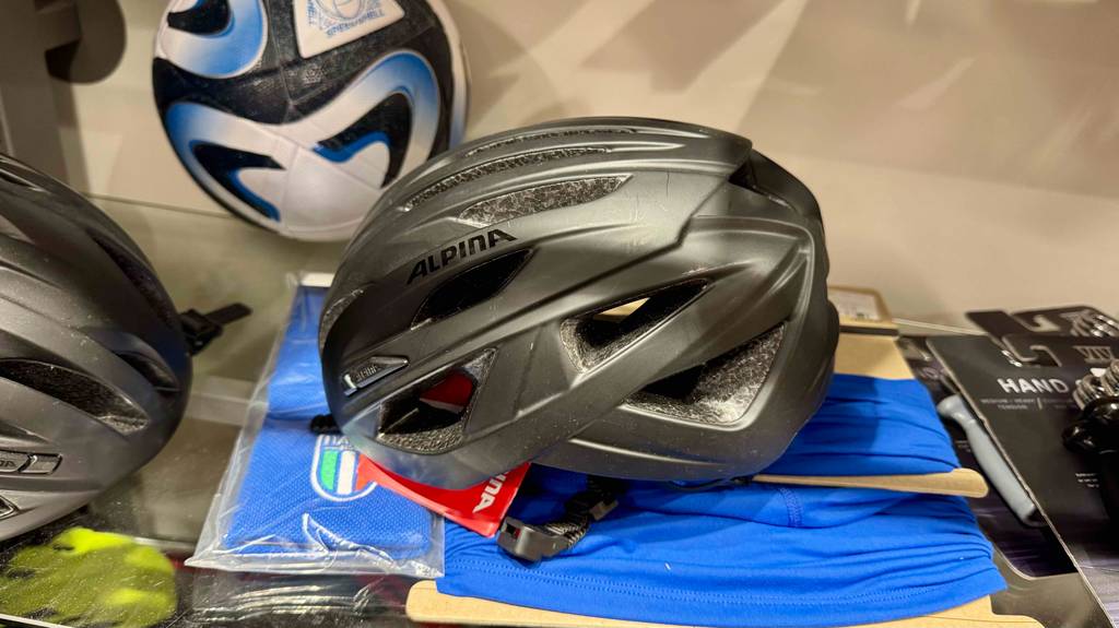Im Test: Der Alpina-Fahrradhelm in Schwarz liegt auf einem Verkaufsregal.