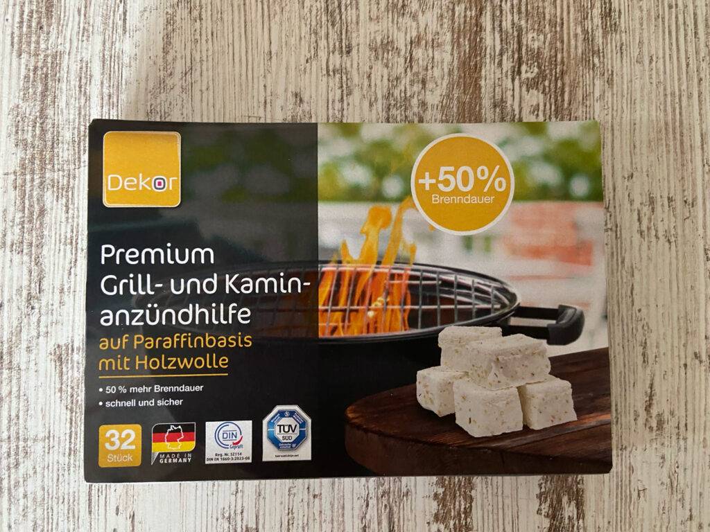 Getestet: Die Anzünder befinden sich in einer Verpackung mit Grill- und Kaminzündhilfe, die auf einer Holzoberfläche liegt.