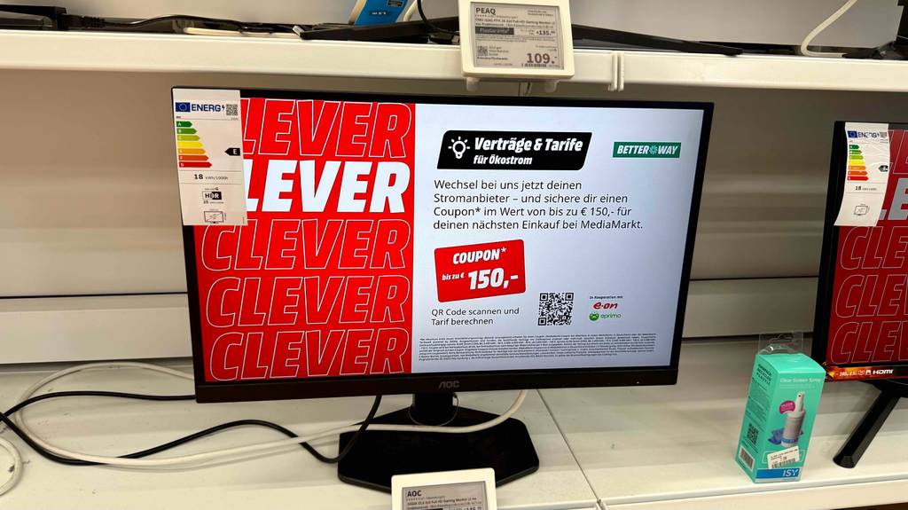 Der getestete AOC-Gaming-Monitor steht mit eingeschaltetem Bildschirm auf einem Ausstellungsregal im Verkauf.