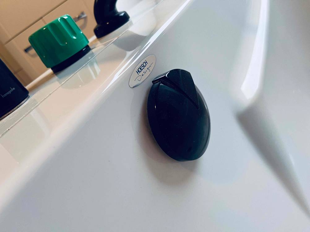 Ansicht einer montierten und getesteten Badewannenarmatur im grün-schwarzen Design der Marke Hansgrohe, mit Fokus auf die Drehelemente für Wasser und Stöpsel.