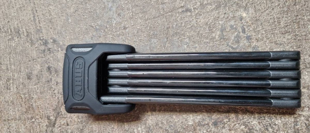 Fahrradschloss im Test: ein Faltschloss in Schwarz liegt zusammengefaltet auf einem boden.