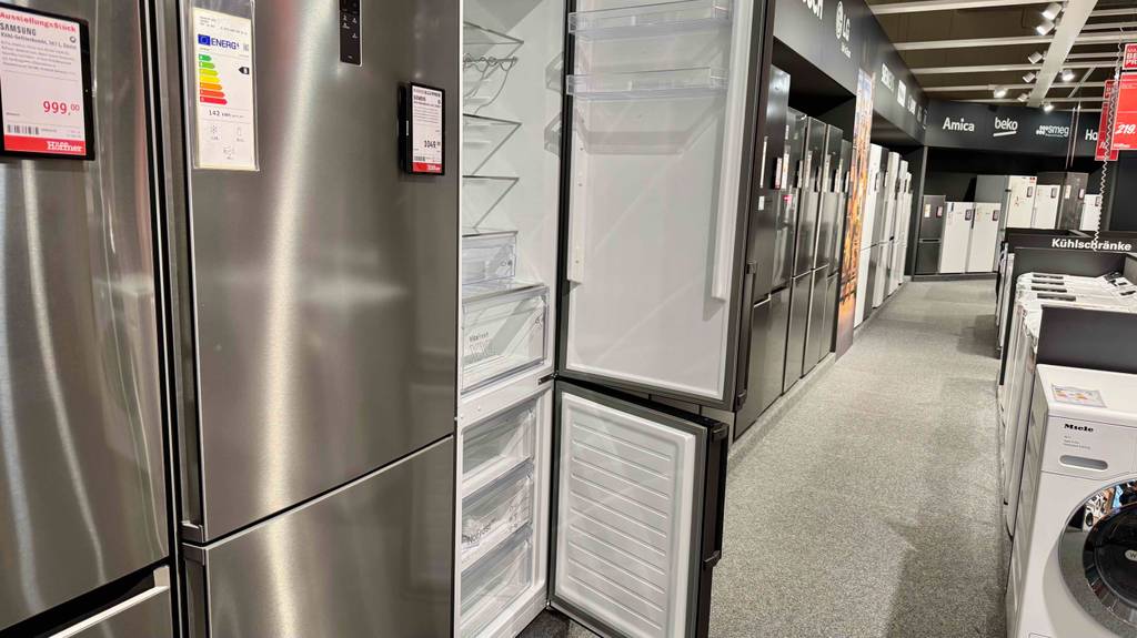 Die silberfarbige getestete Bosch-Kühl-Gefrierkombination steht mit geöffneten Rechtsanschlag-Türen zwischen weiteren Kühl-Gefrierkombinationen in einem Elektrofachmarkt.