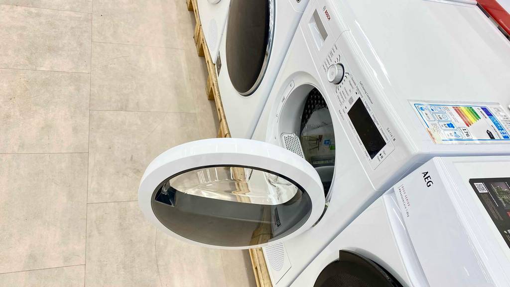 Bosch-Wärmepumpentrockner-Test: ein weißes Modell mit geöffneter vorderer Tür steht zwischen weiteren Frontladern im Geschäft.