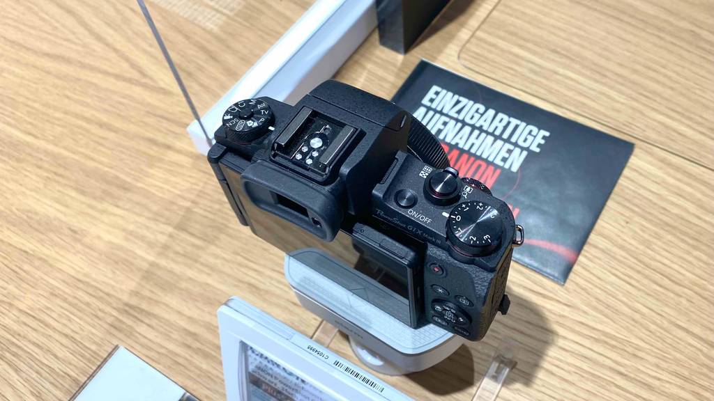 Aufnahme von oben auf eine schwarze Canon-Digitalkamera im Test, mit Fokus auf den integrierten Blitz-Schuh und die Einstellrädchen.