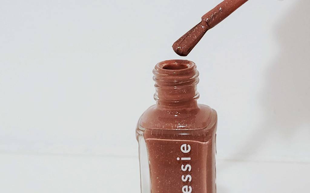 Getesteter Essie-Nagelack befindet sich am Pinsel über der Flasche.