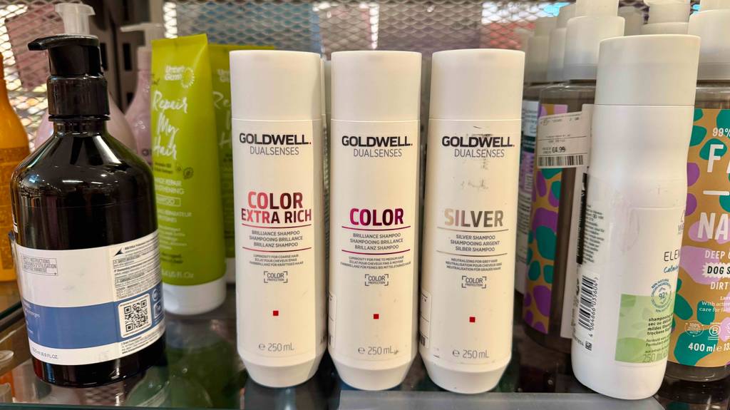 Mehrere weiße Kunststoffflaschen mit getestetem Goldwell-Shampoo befinden sich auf einem Verkaufsregal neben anderen Shampoo-Sorten.
