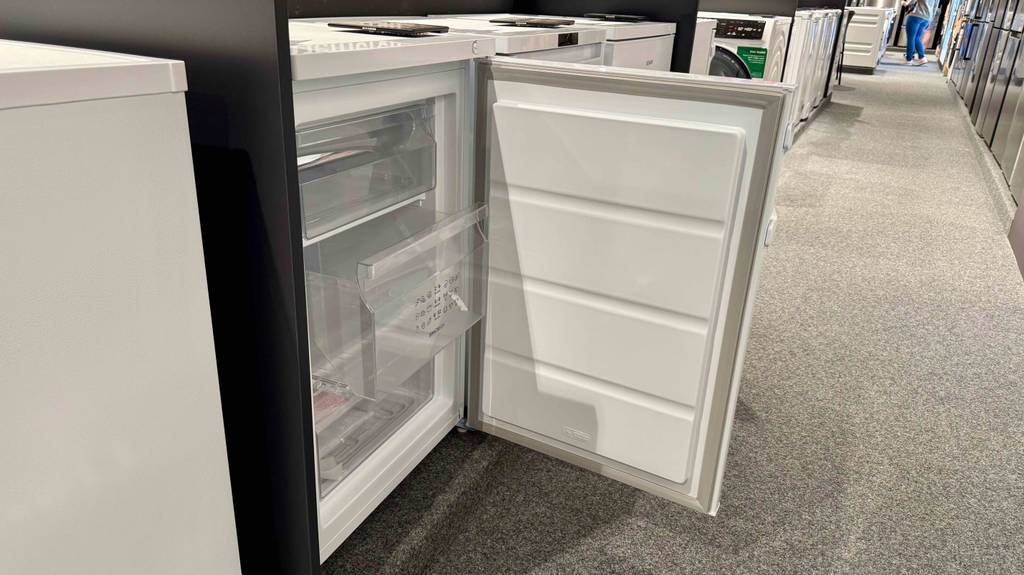 Gorenje-Gefrierschränke-Test: Ein hüfthoher, weißer Gefrierschrank inklusive dreier Schubläden steht mit geöffneter Rechtsanschlag-Tür in einem Verkaufsbereich.