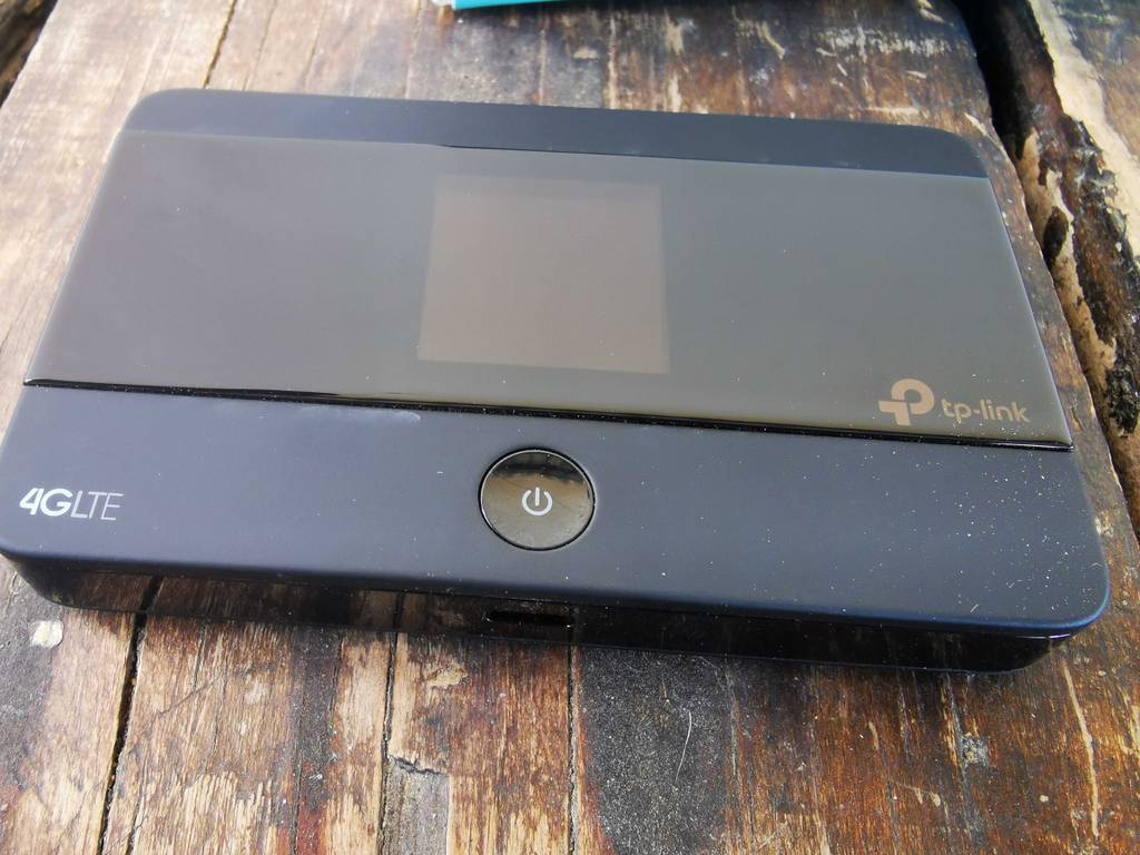 Der schwarze, rechteckige TP-Link-Router im Test steht ausgeschaltet auf einem Holztisch.