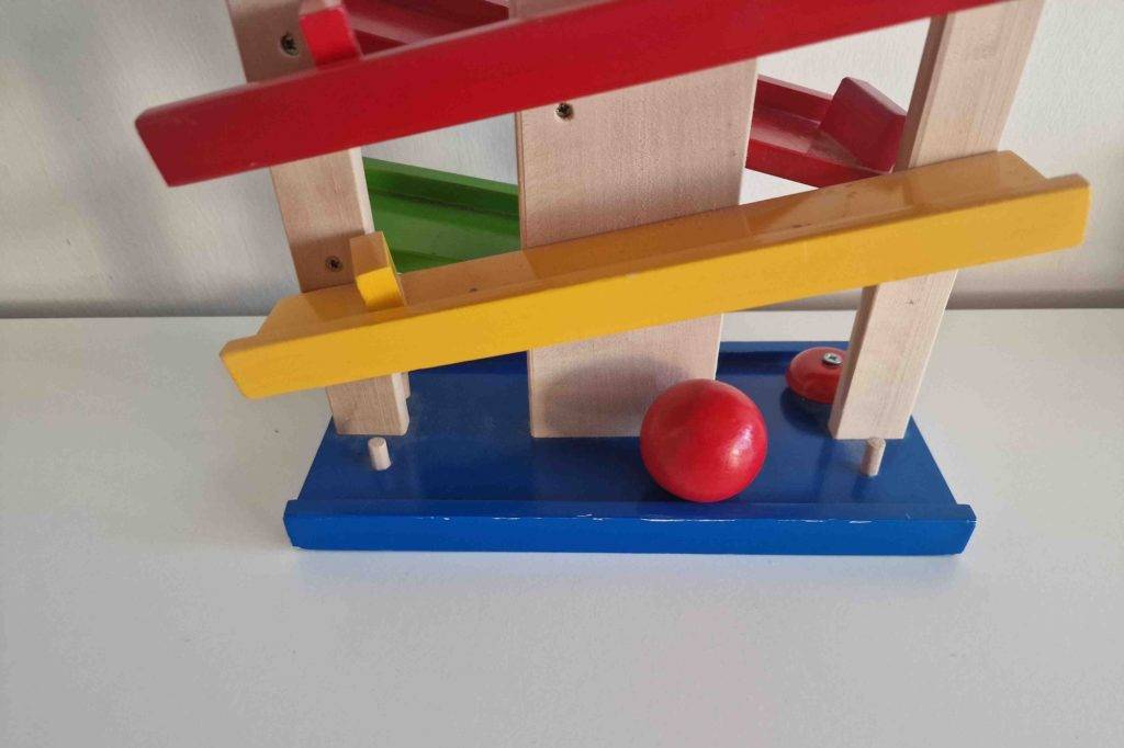 Nahaufnahme einer Kugelbahn im Test: Auf dem mehrfarbigen Modell liegt ein rot lackierter Holzball.