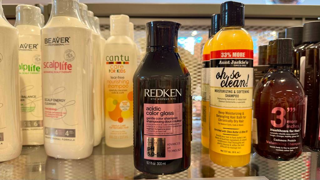 Im Test: Mehrere Redken-Shampoos in dunkelfarbigen 300-ml-Kunststoffflaschen stehen nebeneinander auf einem Verkaufsregal neben anderen Shampoo-Sorten.