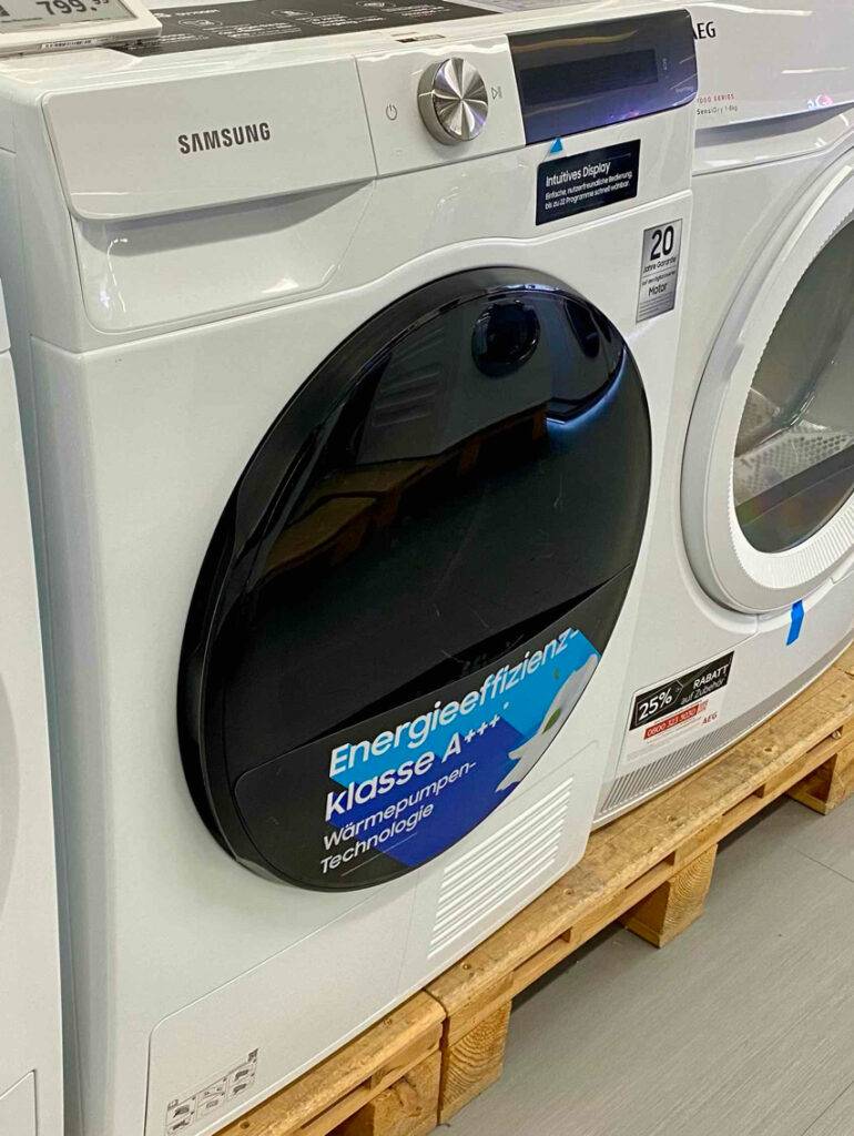 Im Test: Ein Samsung-Trockner mit Aufkleber seiner Energieeffizienzklasse A+++ steht auf einer Holzpalette im Ausstellungsbereich.