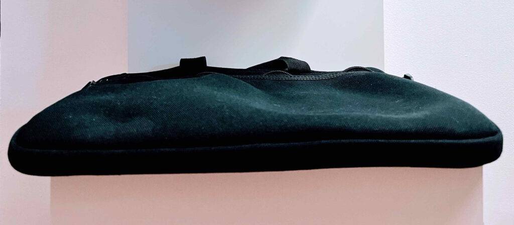 Eine schmal geschnittenen, getestete Tablet-Tasche aus schwarzem Stoff liegt vor einem weißen Hintergrund.