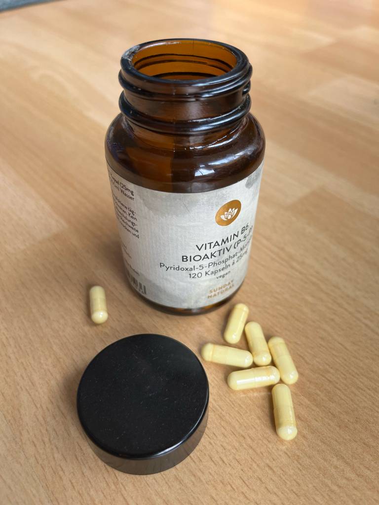 Getestete Vitamin-B6-Präparate in einer blickdichten Verpackung mit Drehverschluss befinden sich auf einer Holzfläche.