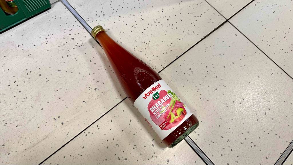 Eine Flasche Voelkel-Saft im Test liegt auf einem Fliesenbelag.