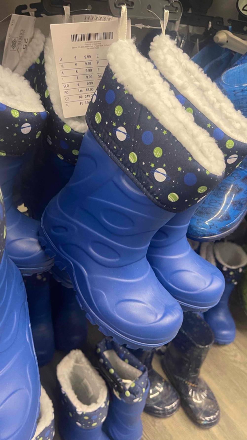 Die blauen getesteten Gummi-Winterstiefel für Kleinkinder hängen an einem Schuhstand im Geschäft.