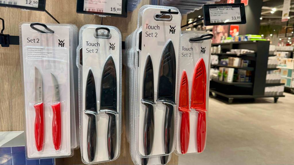 wmf messerset test: Mehrere getestete WMF-Messersets in Schwarz und Rot in Zweierpackungen hängen an einem Verkaufsstand im Supermarkt.