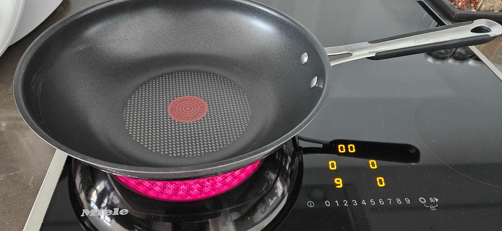 Wokpfannen-Test: ein Modell von Jamie Oliver steht auf einer eingeschalteten Induktionsplatte.