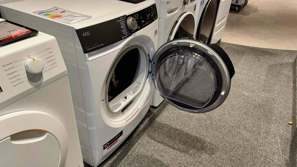 Der getestete AEG-Trockner steht mit geöffneter Tür zwischen weiteren Trocknern auf einer Ausstellungsfläche im Verkauf.