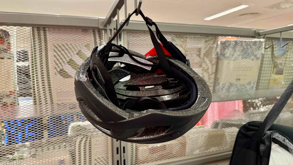 Getestet: Der Alpina-Fahrradhelm in Schwarz hängt an einem Verkaufsregal.