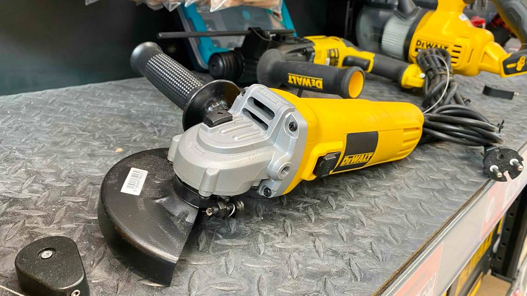 Ein gelber DeWalt Winkelschleifer im Test liegt auf einem grauen Metallregal im Verkaufsbereich neben anderen Dewalt Geräten.