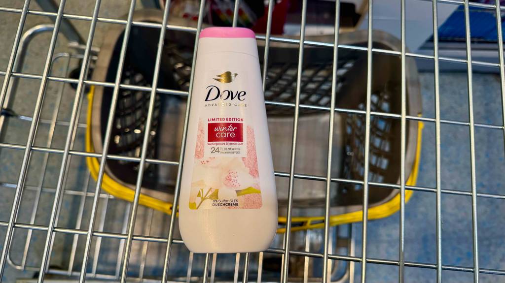 Eine weiße Kunststoff-Quetschflasche mit getestetem Dove-Duschgel liegt in einem Einkaufskorb.