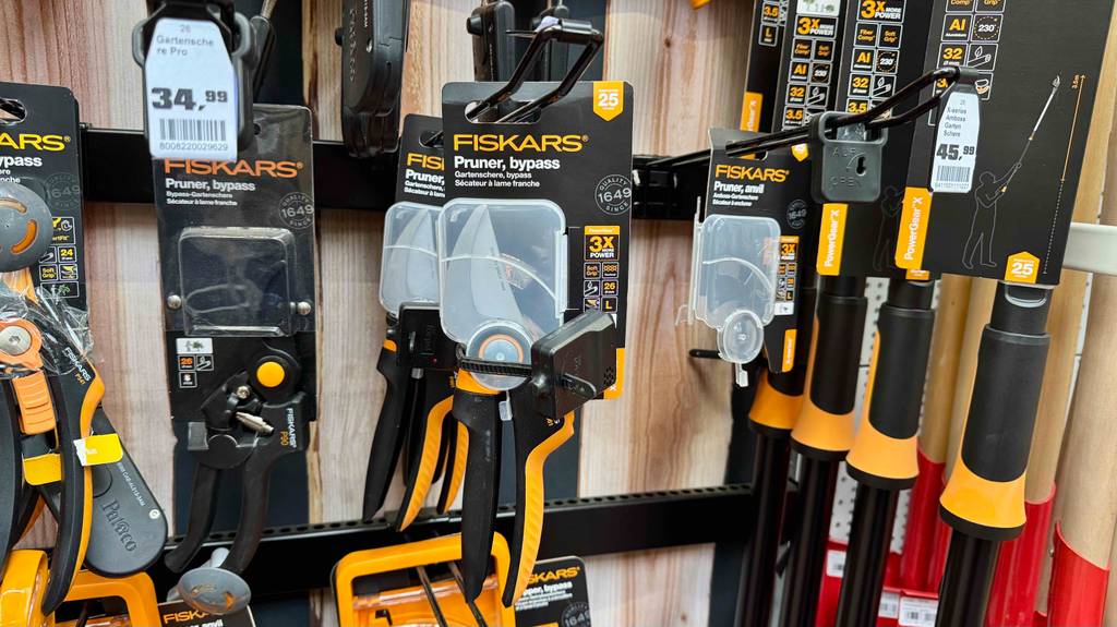 Eine getestete Fiskars-Gartenschere hängt originalverpackt an einem Regal im Gartencenter.