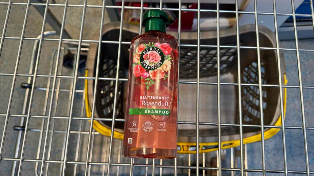 Eine transparente Kunststoffflasche mit Herbal-Essences-Shampoo im Test liegt in einem Einkaufskorb.